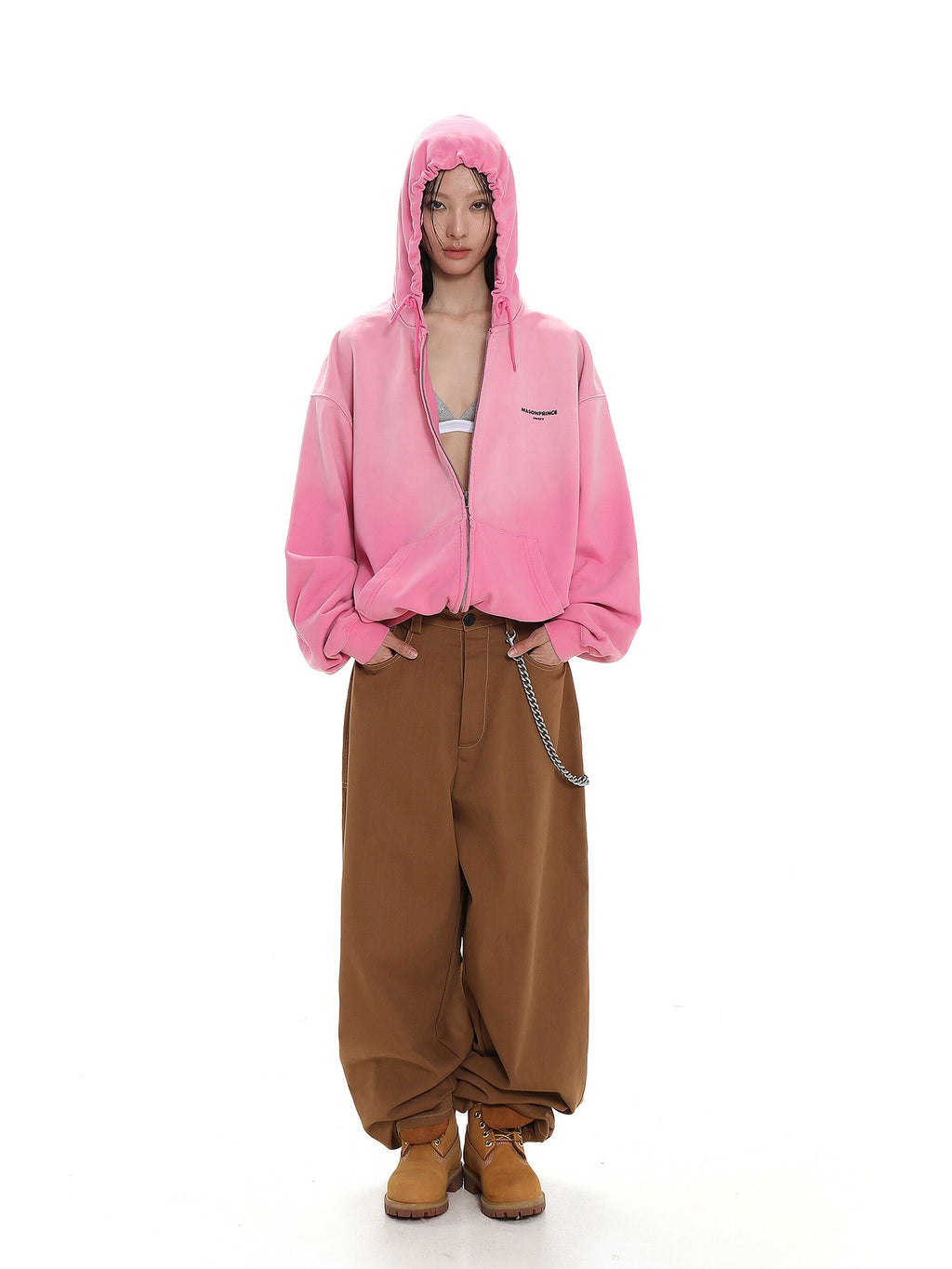 Person wearing a pink hoodie and brown pants on a white background