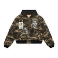 A camouflage hooded bomber jacket with black ribbed trim, a front zipper, and multiple graphic patches on the front and sleeves, shown against a plain white background.