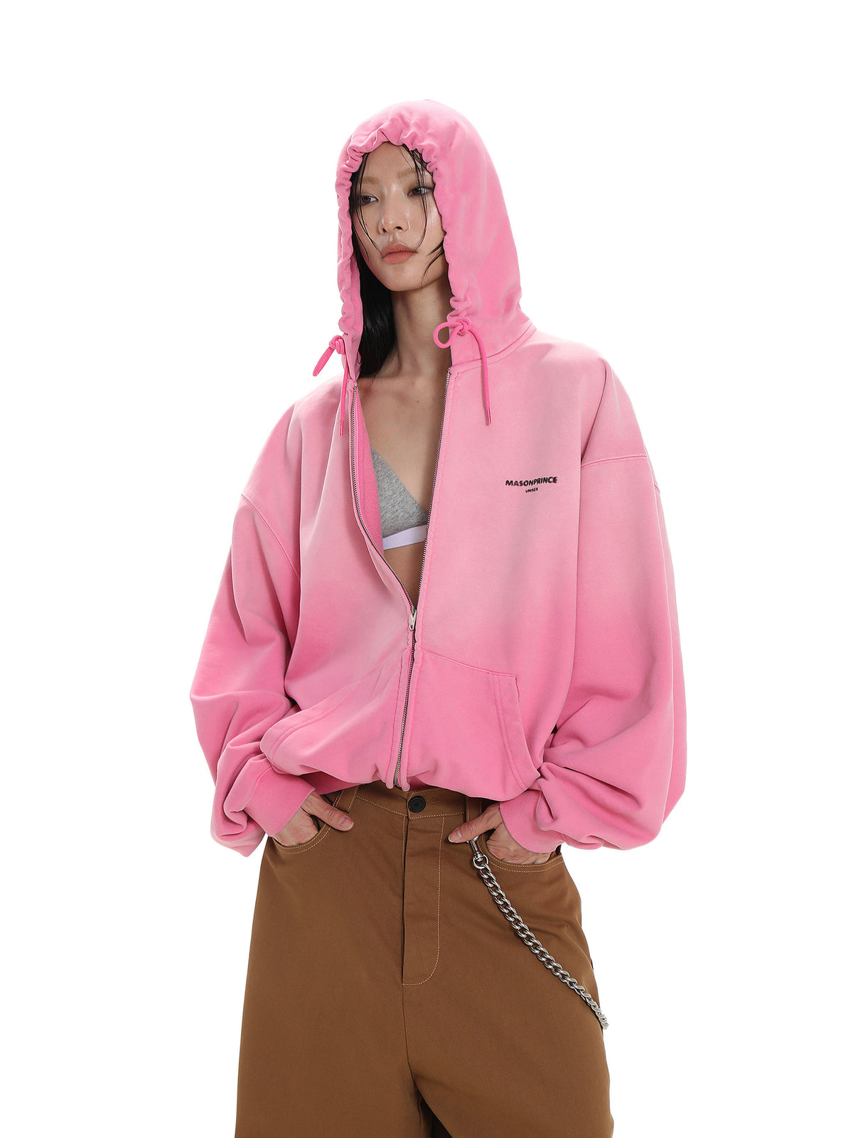 Person wearing a pink hoodie with a brand logo, standing against a white background