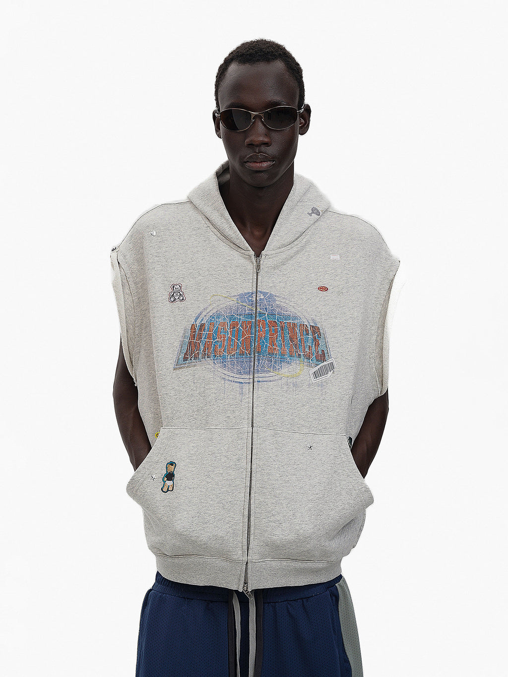 Person wearing a gray sleeveless hoodie with branding on a white background