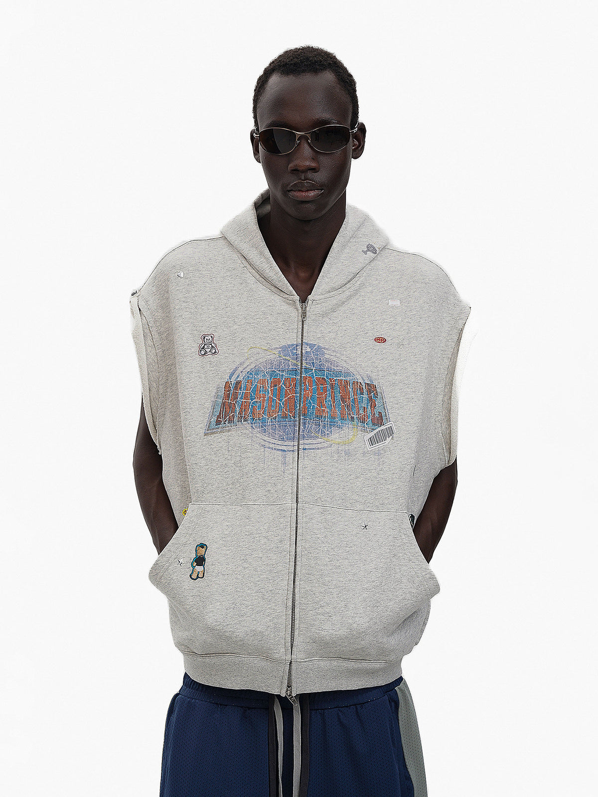 Person wearing a gray sleeveless hoodie with branding on a white background